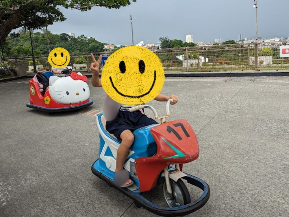 沖縄こどもの国のライドパークで、ミニカーに乗って遊ぶ子どもたち