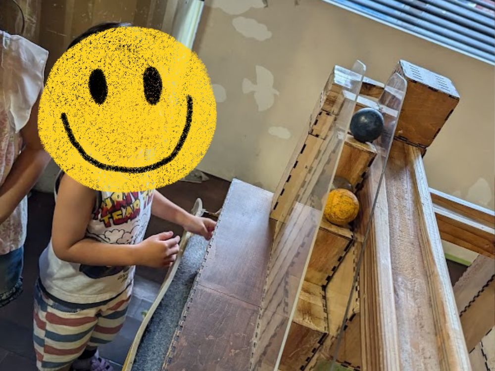 沖縄こどもの国のワンダーミュージアムで、ボールを転がして遊ぶ子ども