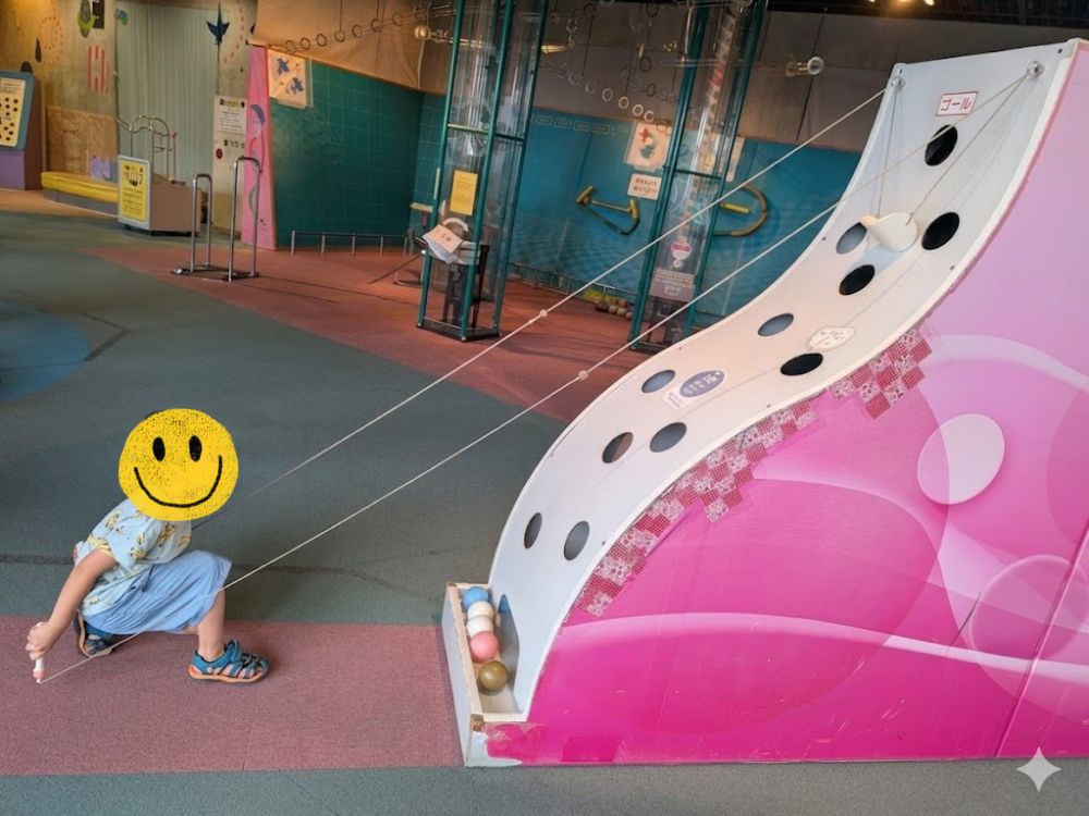 沖縄こどもの国のワンダーミュージアムで、ボールを転がして遊ぶ子ども